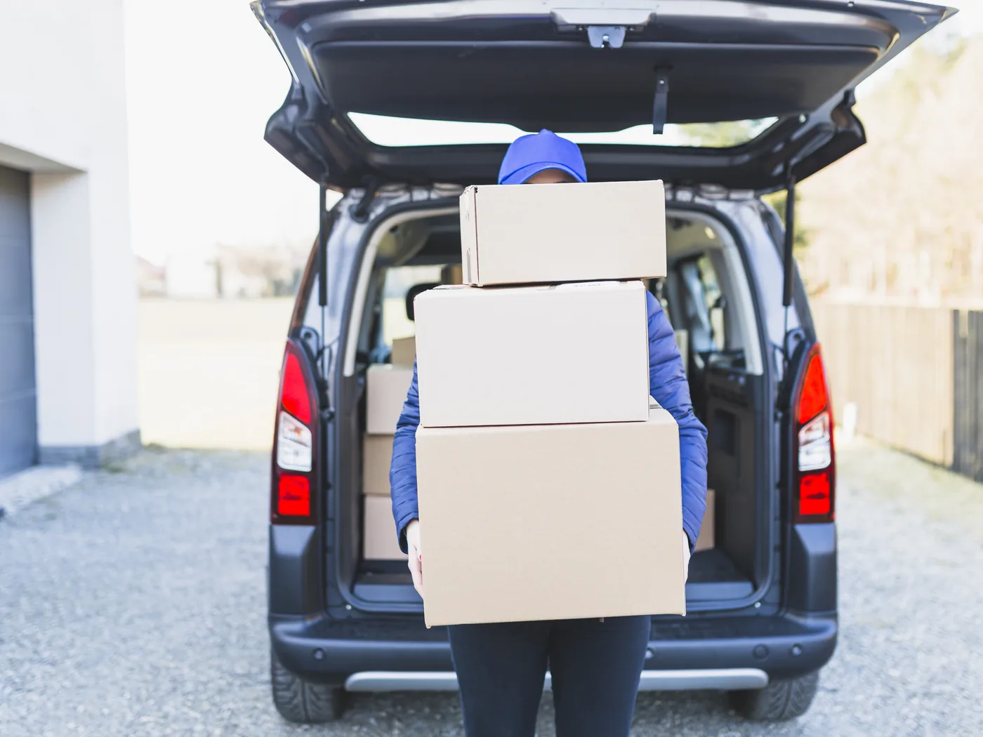 A courier loading boxes into the back of a delivery vehicle